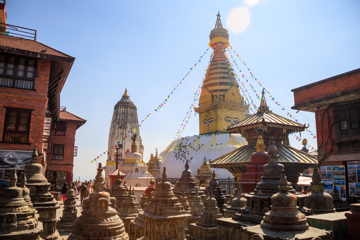 Swayambhu-Stupa in Kathmandu mit Votive Chaityas im Vordergrund und im Hintergrund der Pratappur Tempel
